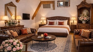 Una habitación con techo alto, vigas de madera a la vista, una cama grande, dos sofás, una mesa de centro y una alfombra.