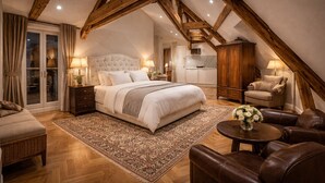 Un dormitorio con una cama grande, vigas de madera, un sofá, una silla y una pequeña mesa con un florero.
