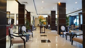 A spacious lobby with a reception desk, seating area, and potted plants.