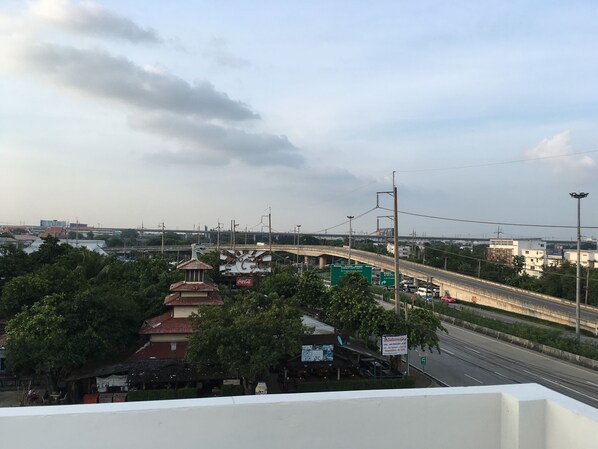 A view of a highway with a bridge in the background, a Coca-Cola sign, and a building with a red roof.
