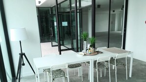Uma sala de reuniões moderna com uma mesa e cadeiras brancas, um abajur e plantas em vasos.