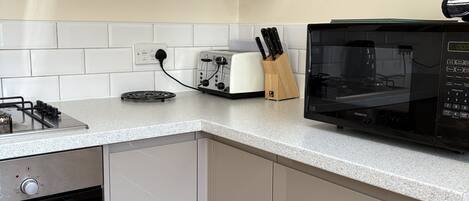 A kitchen with white cabinets, a Bosch oven, a Kenwood microwave, and a toaster.