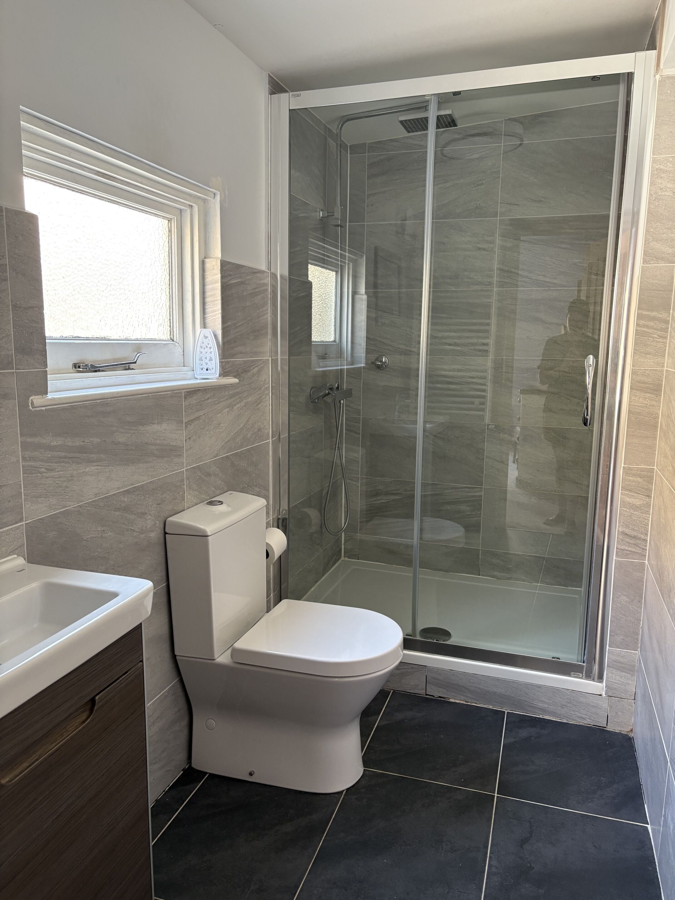 Et moderne badeværelse med toilet, vask og brusekabine med glasvægge.