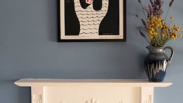 A white fireplace with decorative moldings, a framed artwork above it, and a vase with flowers to the right.