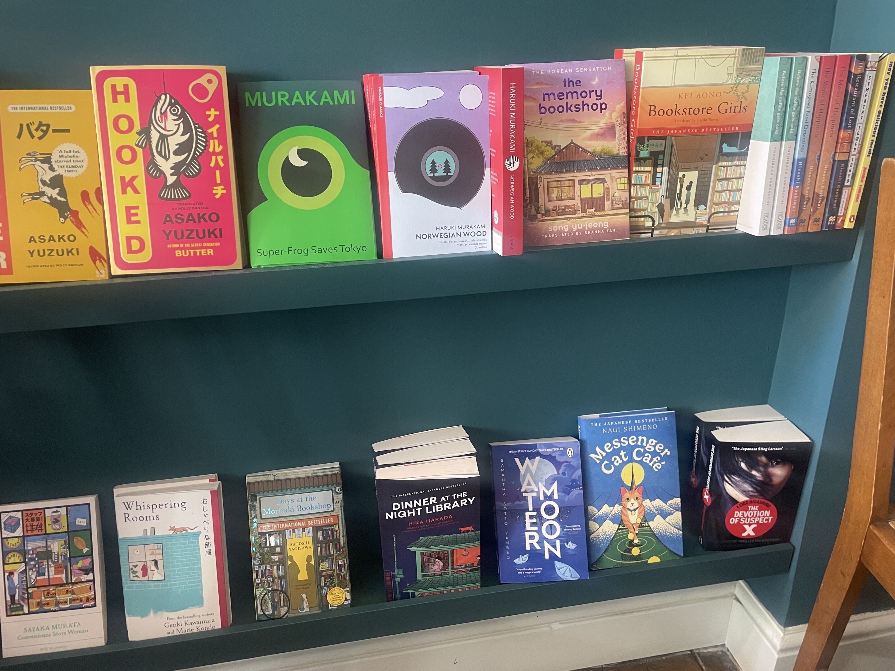 Uma estante com diversos livros, incluindo títulos como 'The Korean Sensation' e 'Bookstore Girls'.
