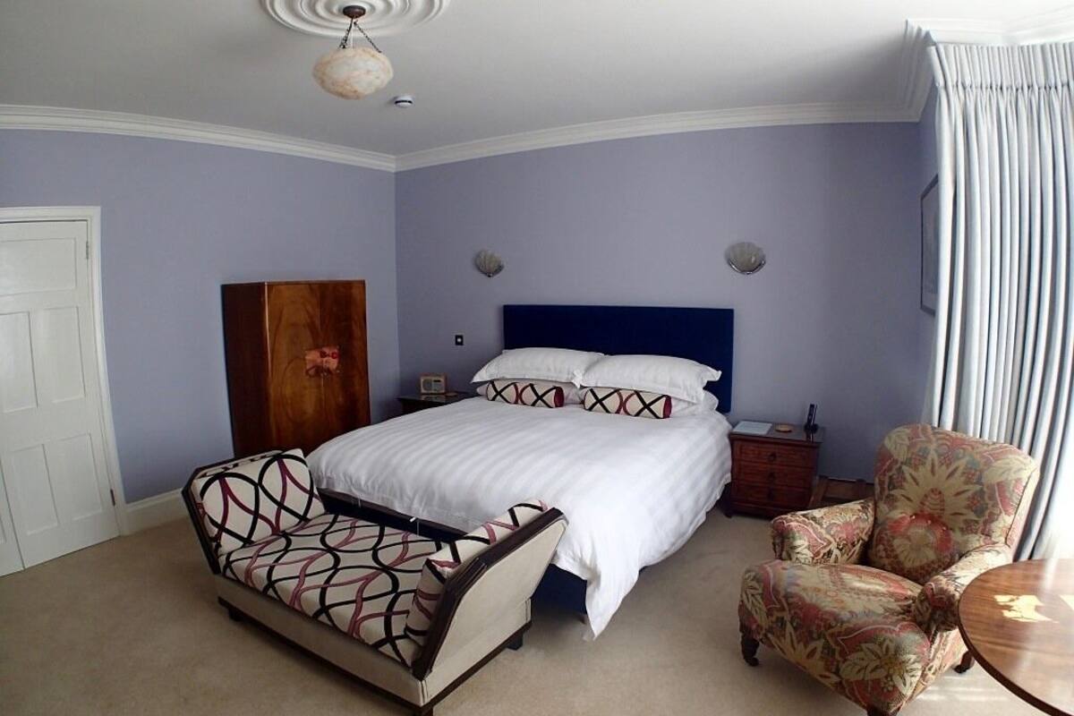 A bedroom with a bed, a nightstand, a dresser, a chair, and a table.