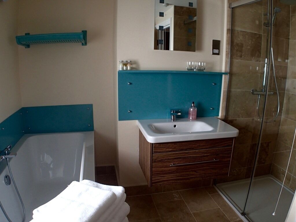 Een badkamer met een bad, wastafel, spiegel en douche.