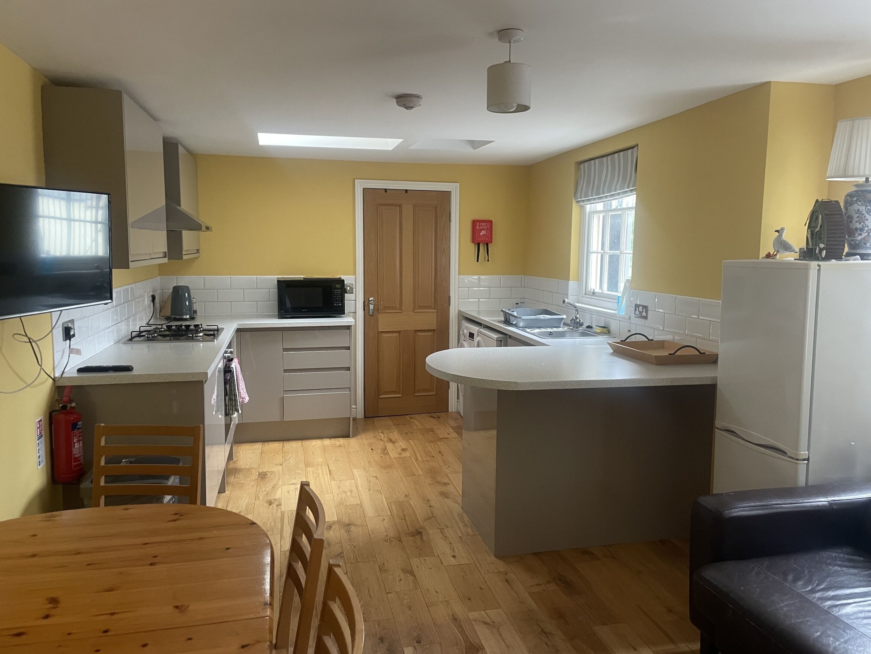 A compact kitchen with a microwave, stove, sink, and a dining area with a table and chairs.