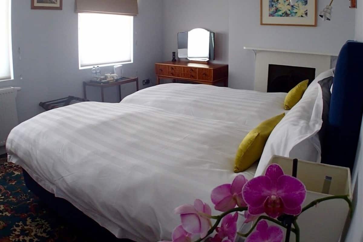A hotel room with a large bed, a dresser, a mirror, and a window.
