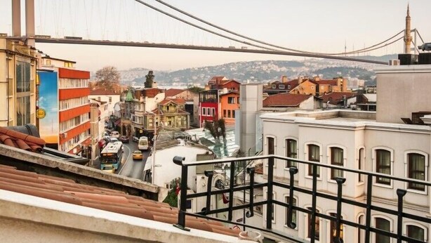 A balcony with a table set for a meal, overlooking a cityscape with a bridge and buildings. - New Bosphorus Hotel (Istanbul)