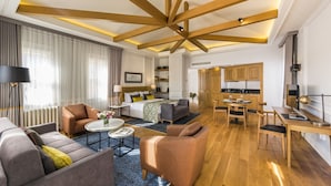 A modern hotel room with a wooden ceiling, a living area with sofas and a coffee table, a kitchen with wooden cabinets, and a dining area with a table and chairs. - New Bosphorus Hotel (Istanbul)