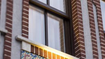 Fachada de edificio con una ventana que presenta un detalle decorativo amarillo y un colorido diseño de azulejos en la parte inferior.