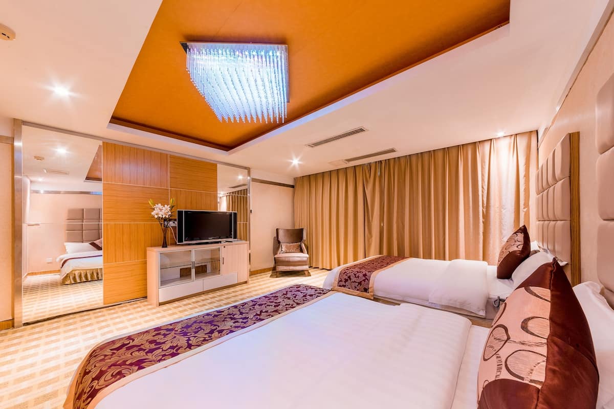 A hotel room with a large bed, a TV, a seating area, and a view of the room.