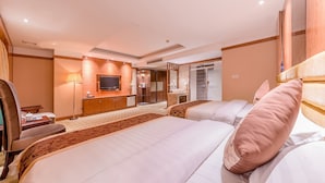 Habitación de hotel con una cama grande, escritorio, televisor, baño y vistas al exterior.