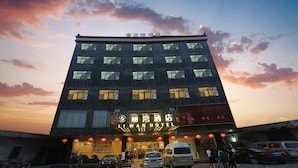 Un hotel con fachada moderna, varios pisos y señalización iluminada.