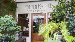 Een winkelgevel met een houten deur en een bord waarop 'Yoo Yen Pen Sook' staat.