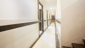 A long, well-lit hallway with white walls and a black stripe running down the center. - FabHotel Parimeet Navi Mumbai (Navi Mumbai)