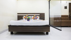 A modern bedroom with a wooden bed, white bedding, and colorful geometric pillows. - FabHotel Parimeet Navi Mumbai (Navi Mumbai)