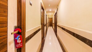 A hotel hallway with wooden doors, a 'DON'T DISTURB' sign, and a marble floor. - FabHotel Parimeet Navi Mumbai (Navi Mumbai)