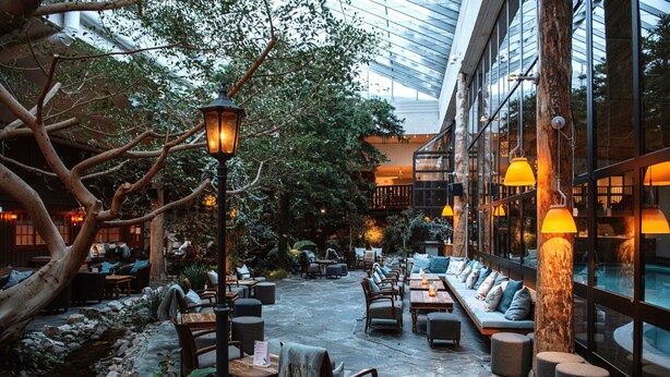 Un patio interior con suelo de piedra, muebles de madera e iluminación ambiental.