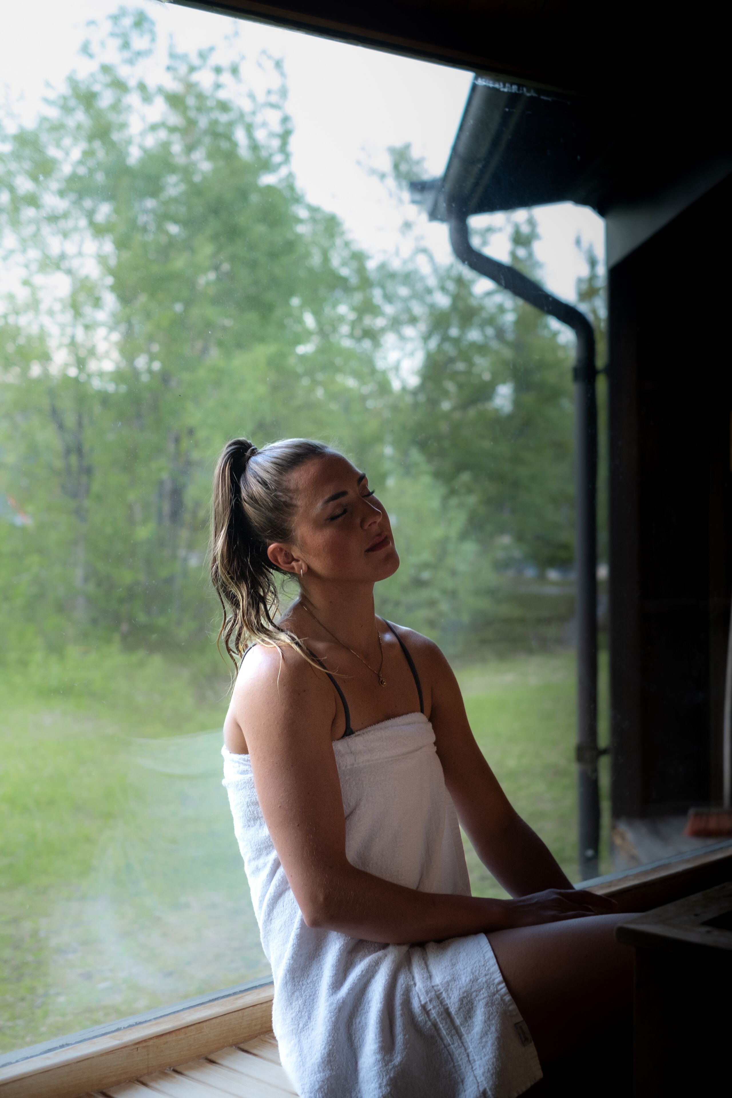 A person sitting by a window with a view of trees and grass.