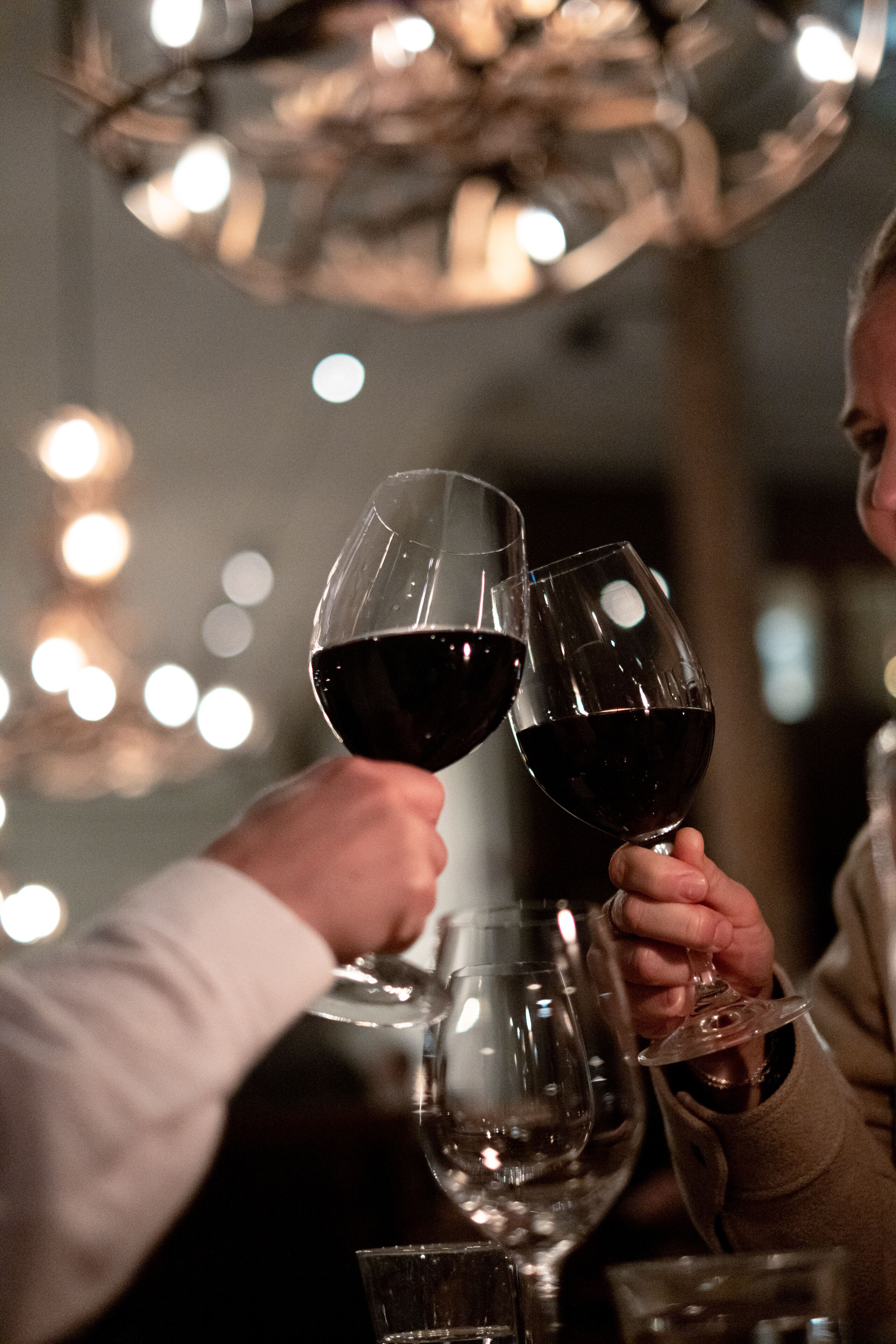 A person holding two wine glasses filled with red wine.