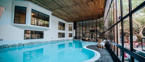 An indoor swimming pool with a wooden ceiling and large windows.