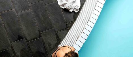 Una piscina con borde de azulejos y una toalla blanca en el suelo.