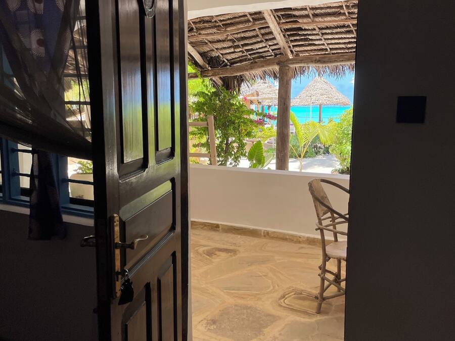 An open door leading to a covered outdoor area with a view of the ocean.
