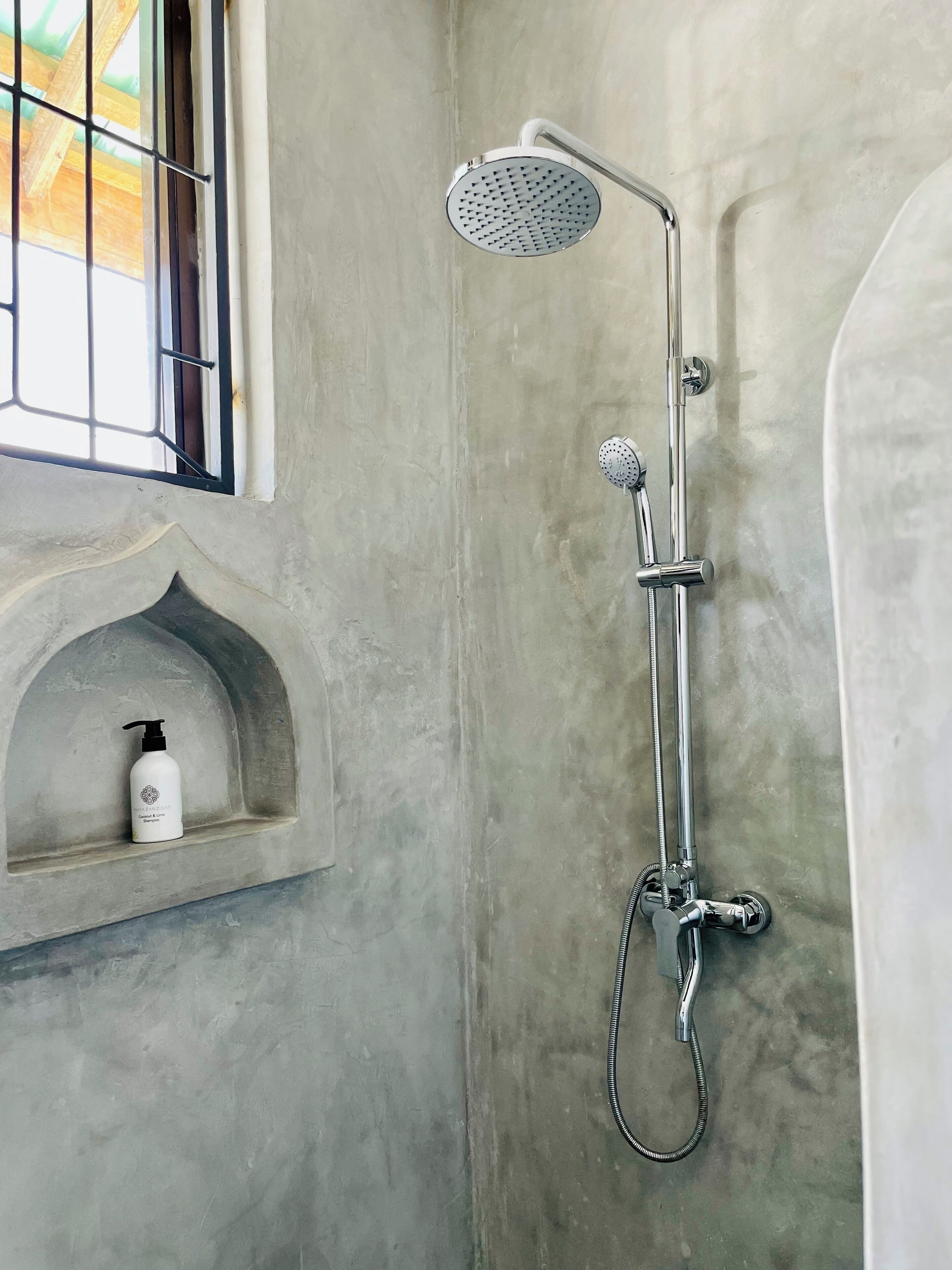 Une douche équipée d’un pommeau de douche à main et d’un robinet mural.