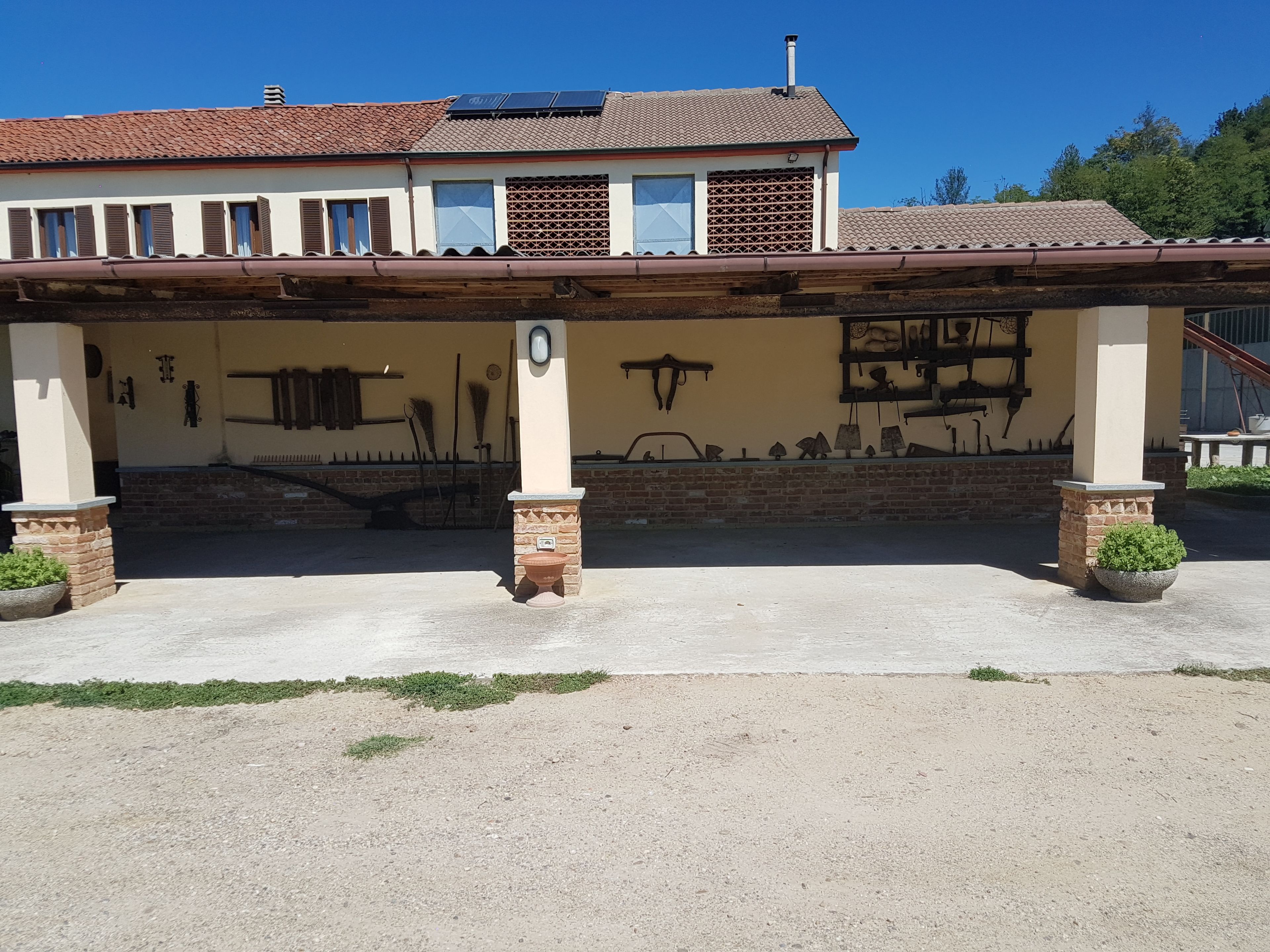 Un bâtiment doté d’un patio couvert, de panneaux solaires sur le toit et d’un mur décoré de divers outils et équipements.