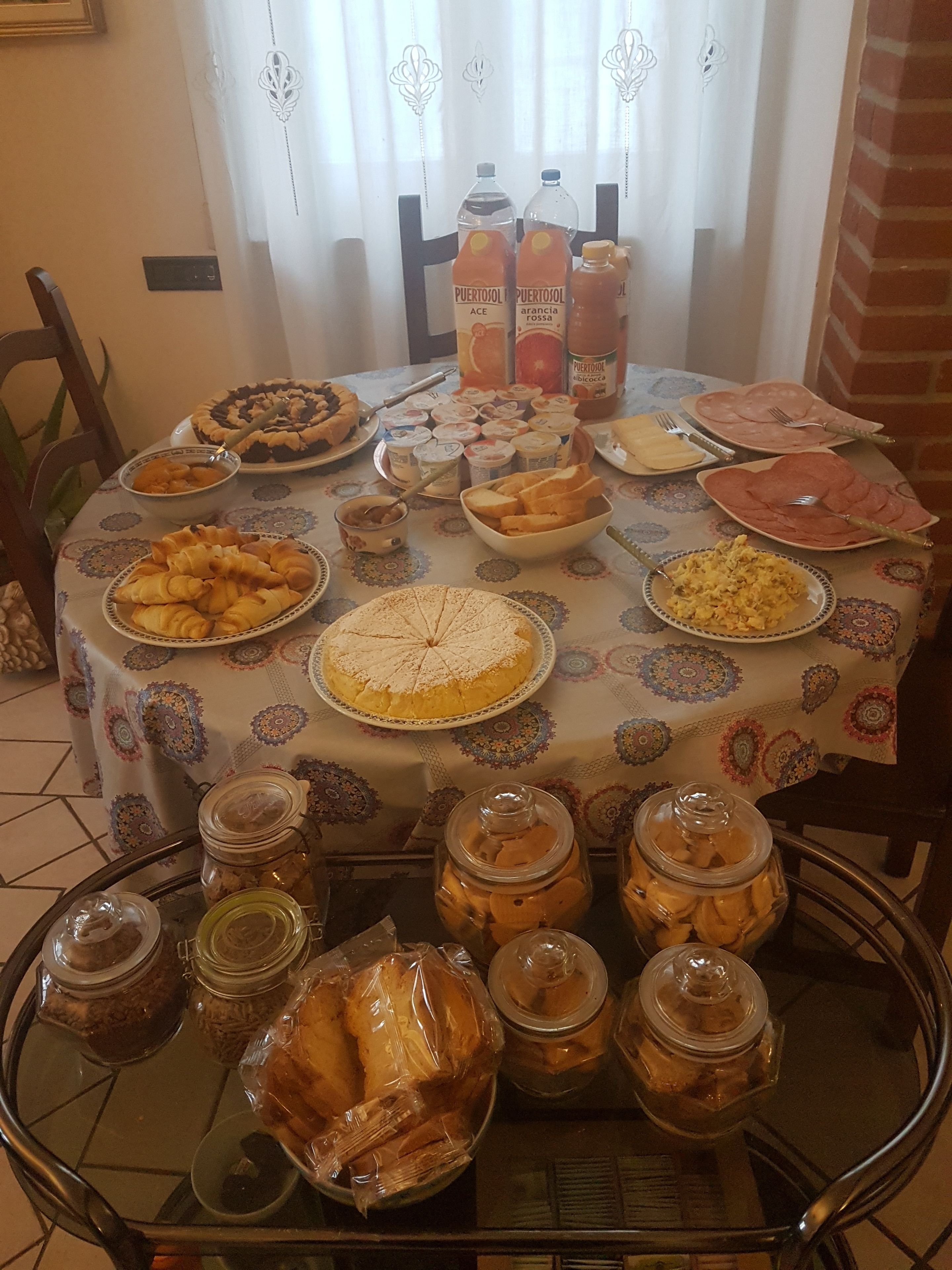 Une table à manger avec divers aliments et condiments, notamment des pâtisseries, un gâteau et des bouteilles de jus de fruits.