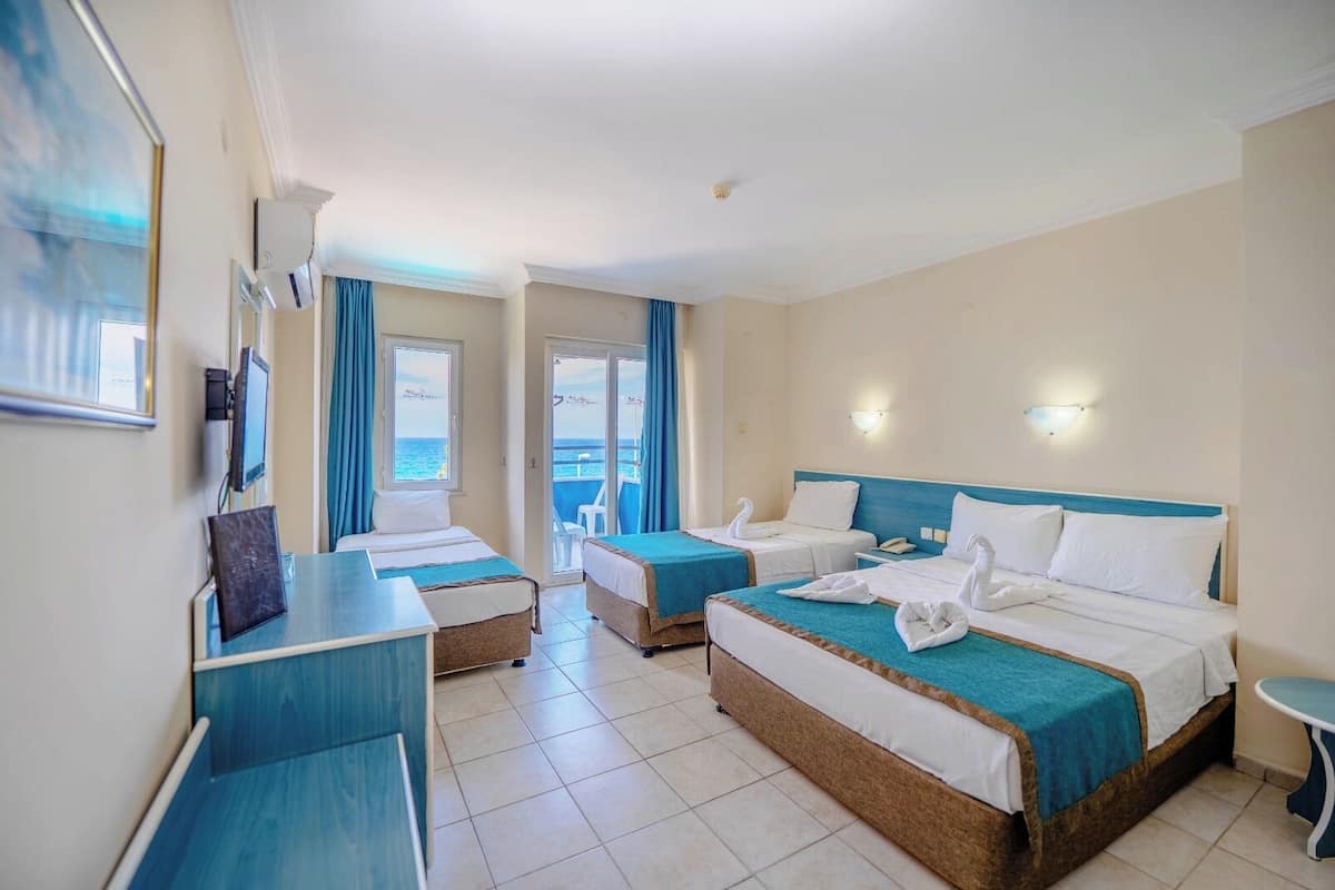 Habitación de hotel con dos camas, un escritorio y vista al mar.