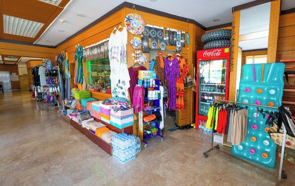 Una tienda con diversos artículos a la vista, incluyendo ropa, accesorios y un refrigerador de Coca-Cola.