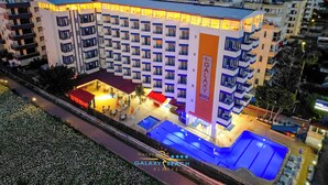 Un hotel de varios pisos con piscina en la azotea y zona de estar al aire libre.