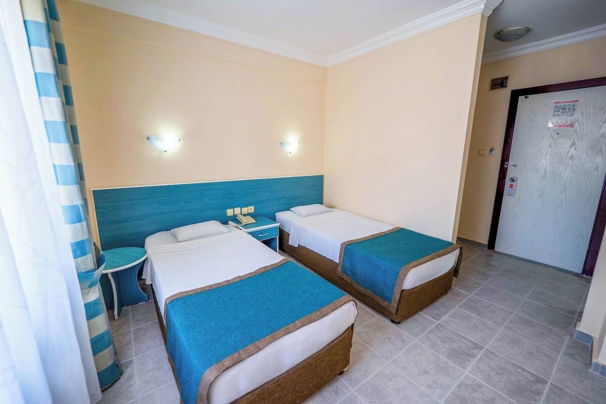Una habitación de hotel con dos camas, una mesita y una puerta.
