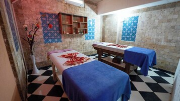 Ein Zimmer mit zwei Betten, einer kleinen Ablagefläche und einem gefliesten Boden.