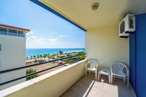 A balcony with a view of the beach and ocean, two white plastic chairs, and an air conditioning unit. - Galaxy Beach Hotel (Alanya)