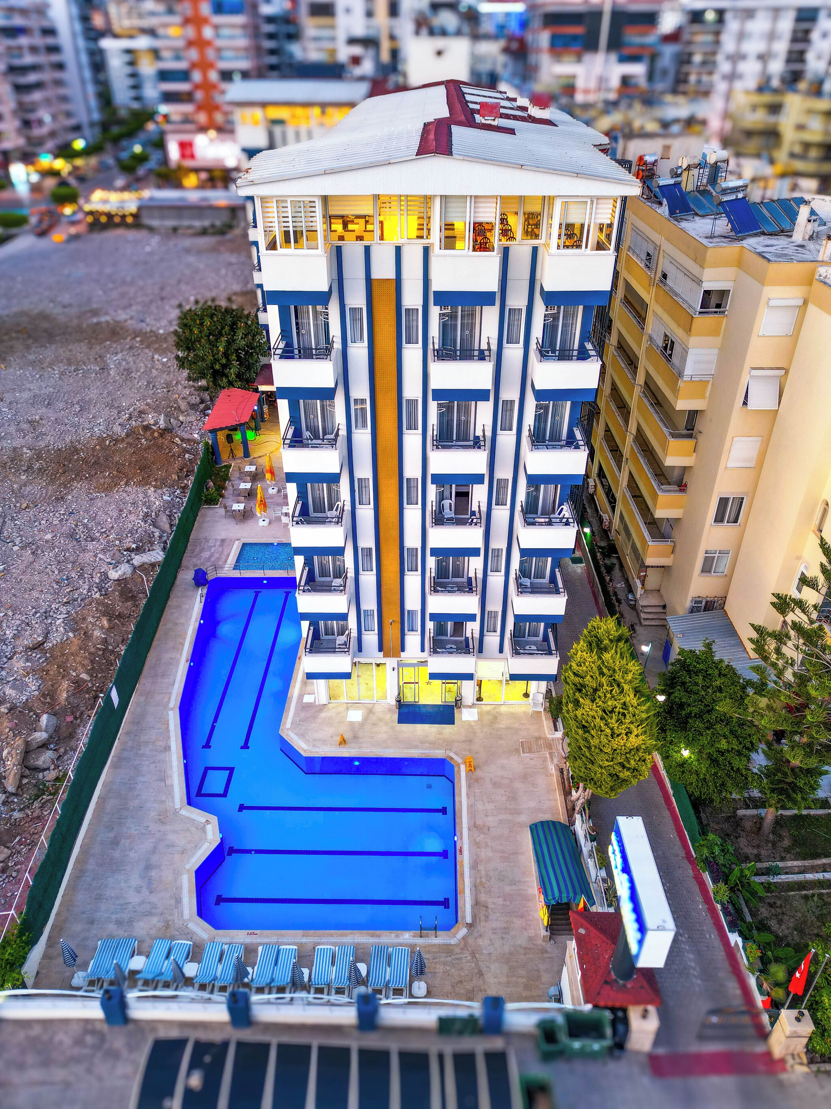 A multi-story hotel with a swimming pool and sun loungers.