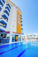 A hotel with a pool area, a sign reading "Galaxy Beach", and a building with blue and white balconies.