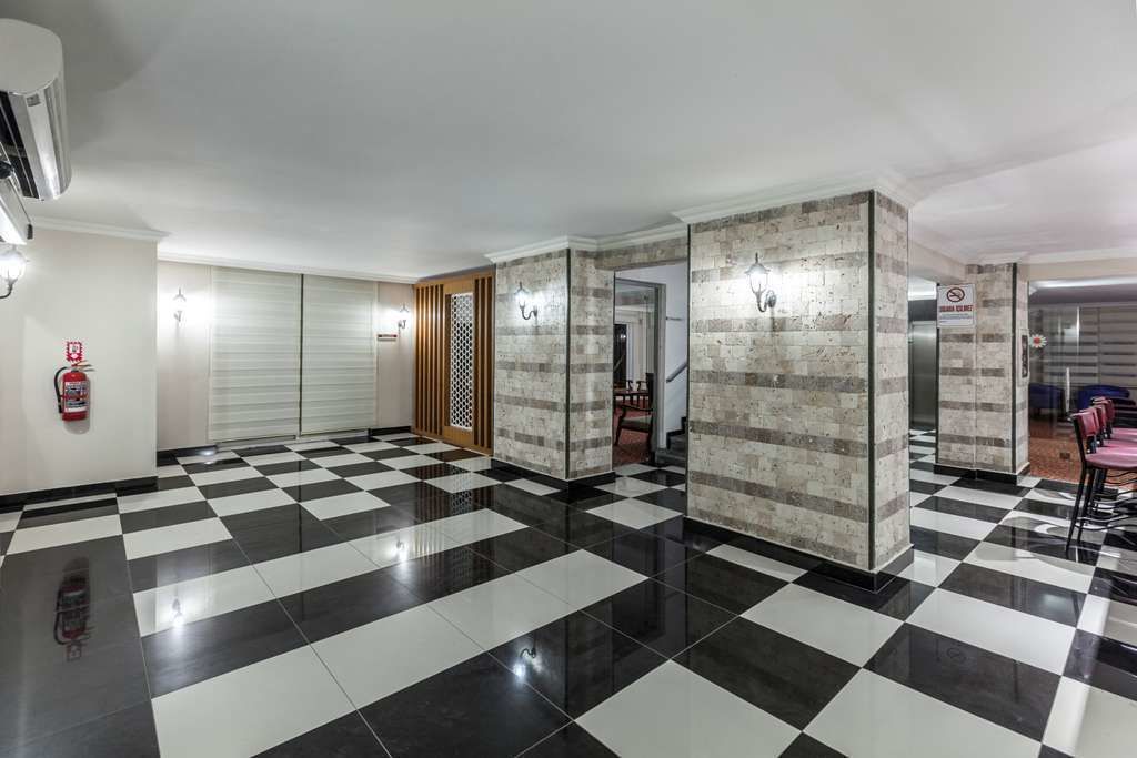 A lobby with a checkered floor, a fire extinguisher, and a no-smoking sign.