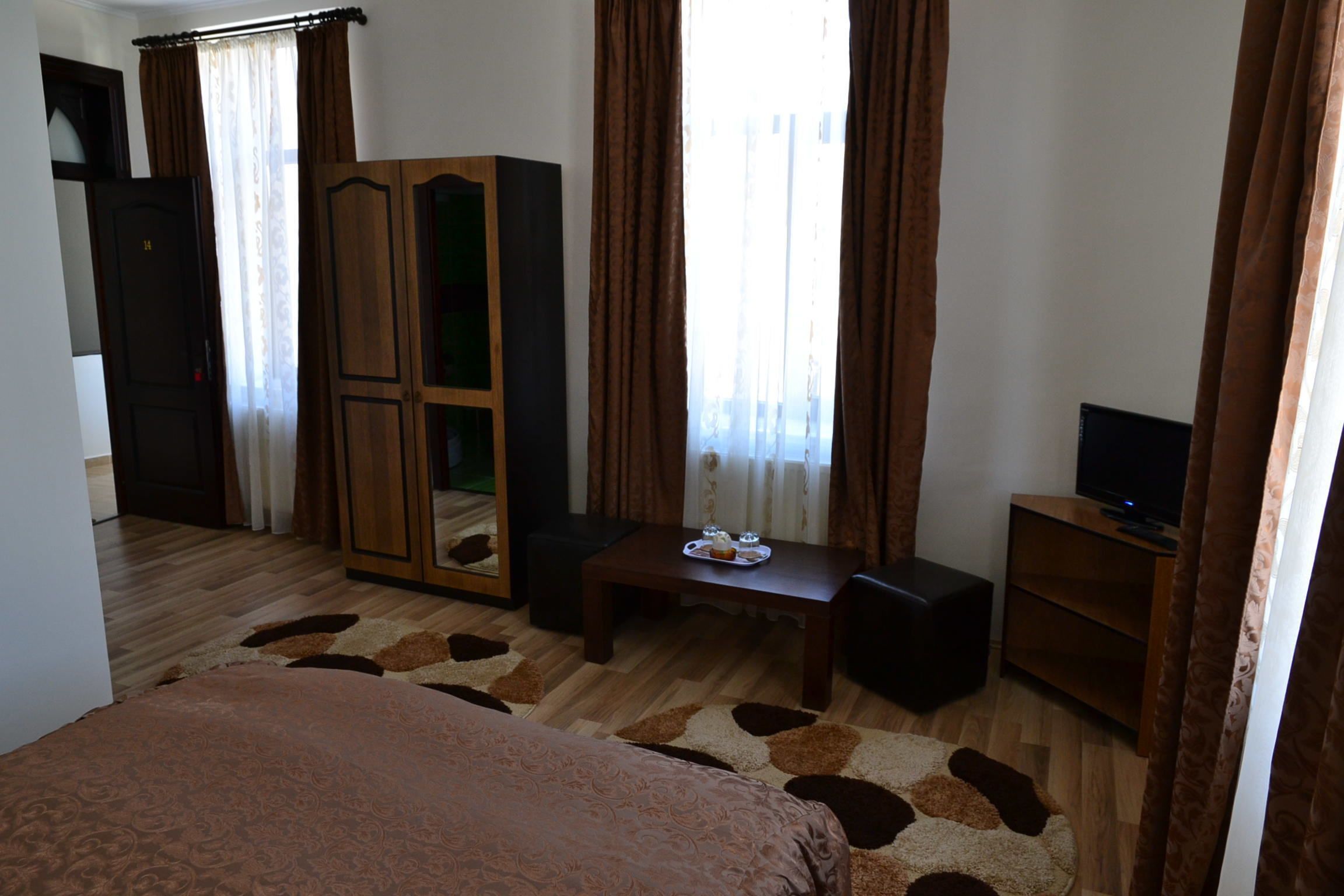 Een slaapkamer met een bed, een houten kledingkast, een televisie en een klein tafeltje met dienblad.