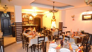 A restaurant with multiple dining tables set for a meal, a bar area with bottles, and a chandelier. - Porto Franco Residence (Braila)