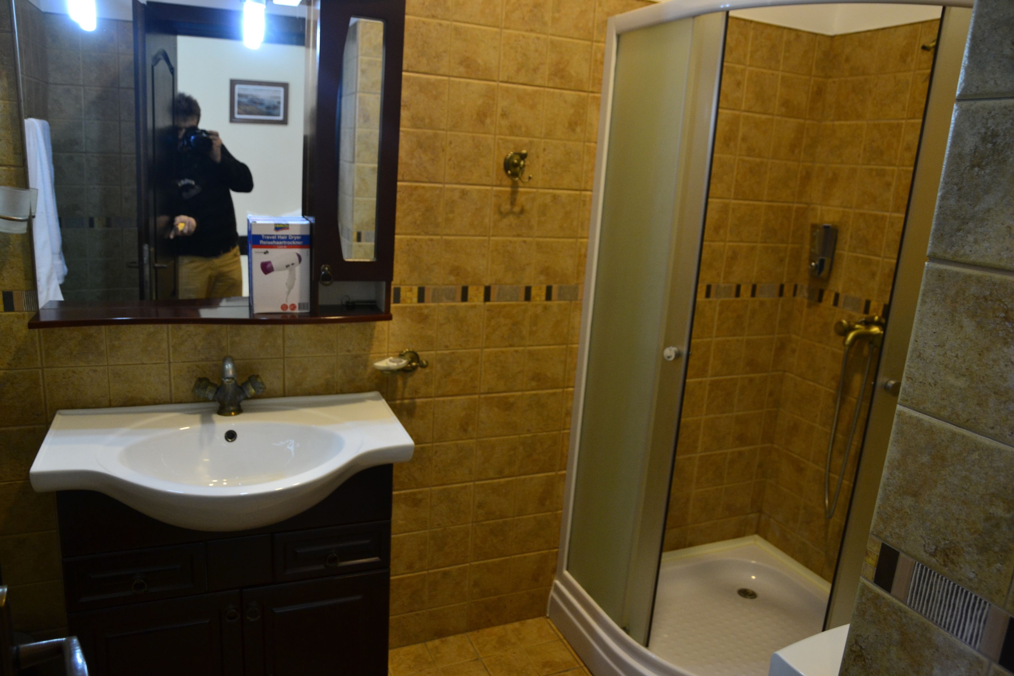A bathroom with a sink, mirror, and shower.
