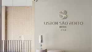 Un interior moderno con un cartel de "Lisbon São Bento Hotel" y una zona de estar con otomanas.