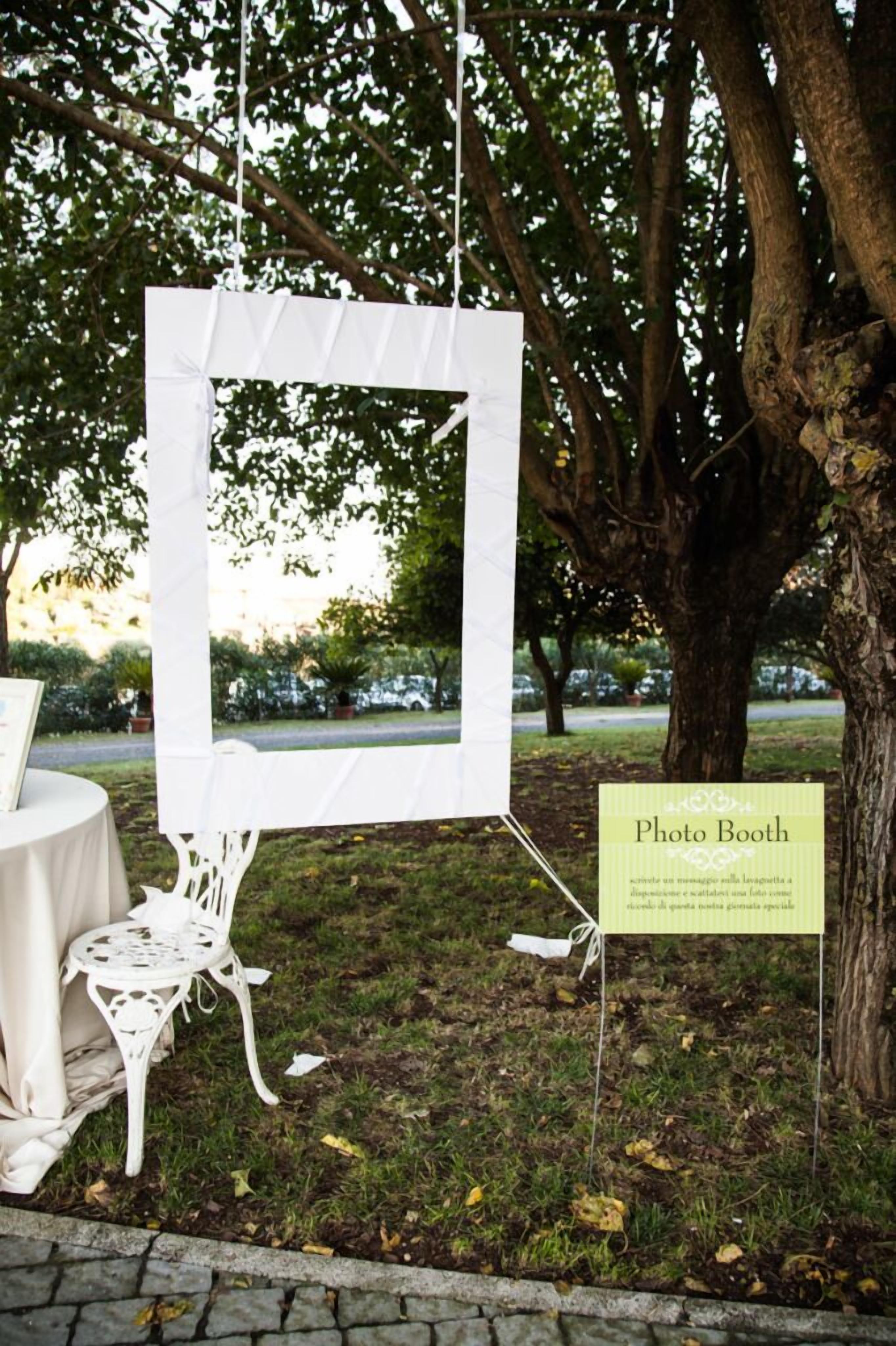Uma cabine de fotos montada com fundo branco e um letreiro indicando sua finalidade.