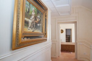 Un corridoio con un quadro di grandi dimensioni appeso alla parete, una porta che dà su un'altra stanza e un pavimento decorato.