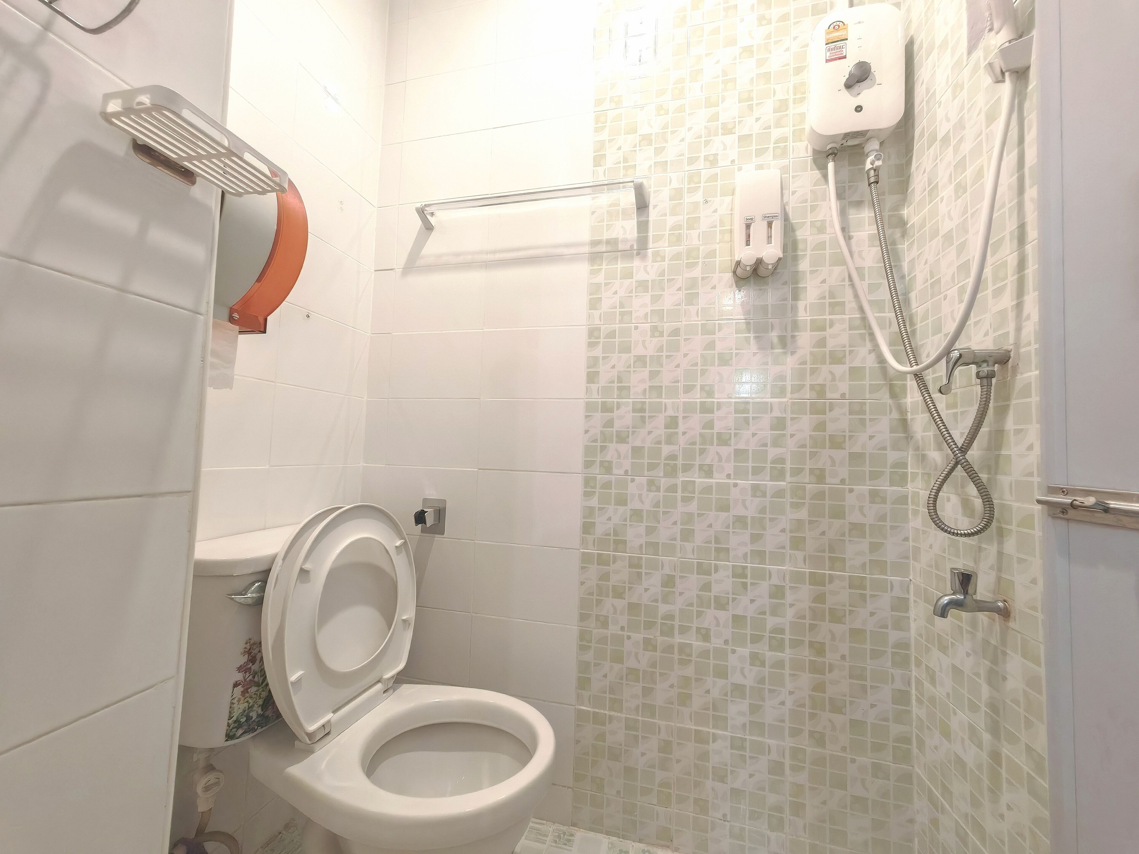 A bathroom with a toilet, a shower, and a hand dryer.