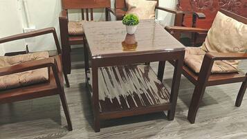 A common room with a wooden table, four chairs, and a decorative vase.