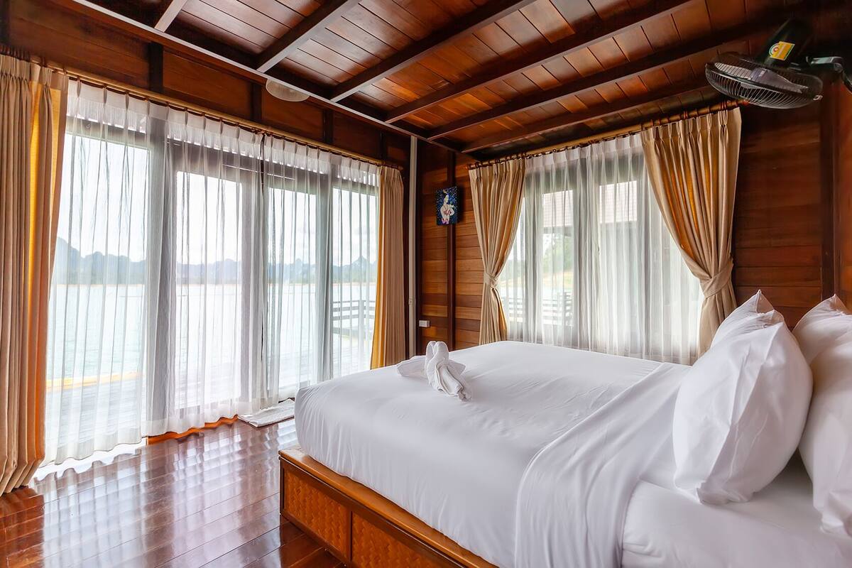 Ein Hotelzimmer mit einem großen Bett, Holzbalkendecke und Blick aufs Wasser.